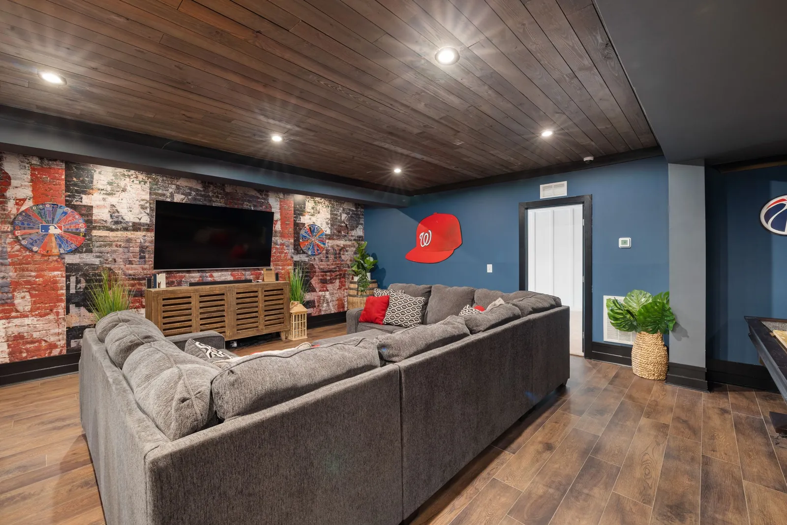 A finished basement rec room with painted walls and a wood ceiling