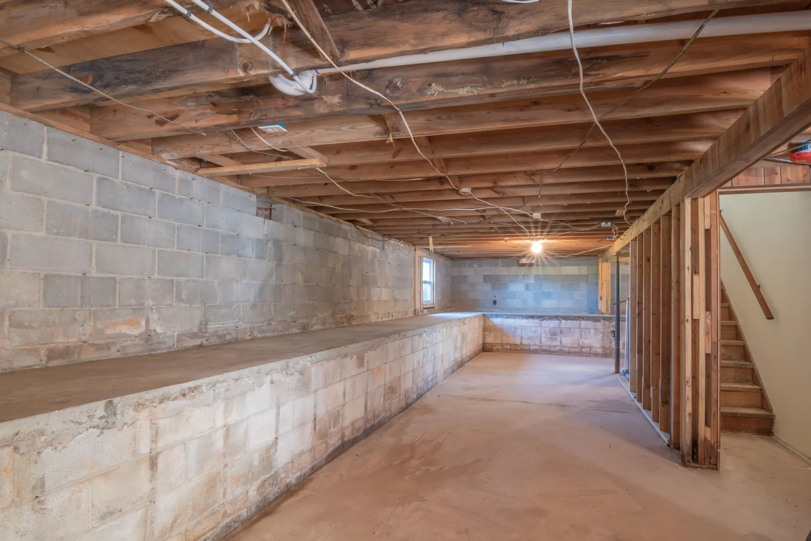 An unfinished basement with exposed joists and block walls