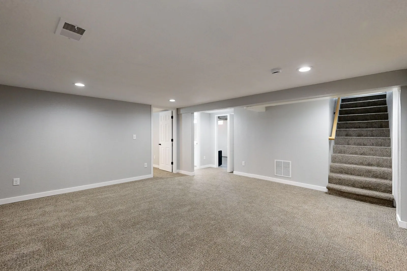 A finished basement with smooth painted walls and recessed lighting