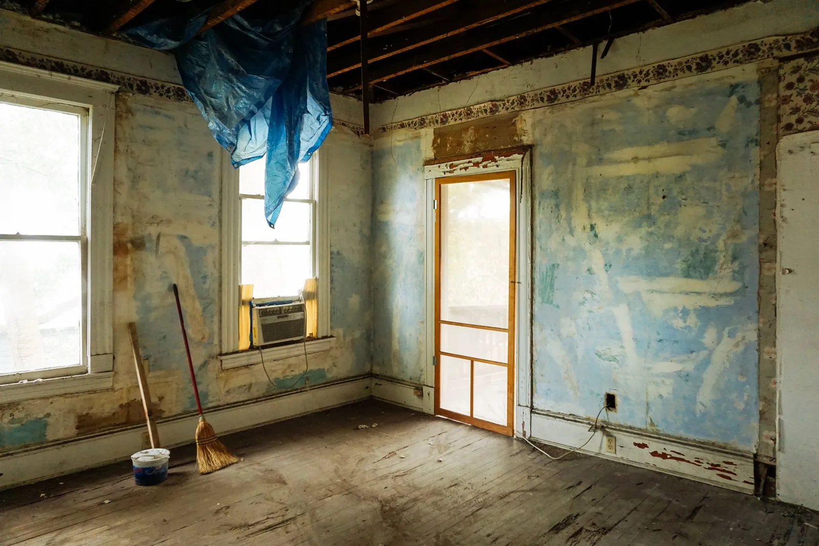 A gutted room with peeling walls and exposed framing