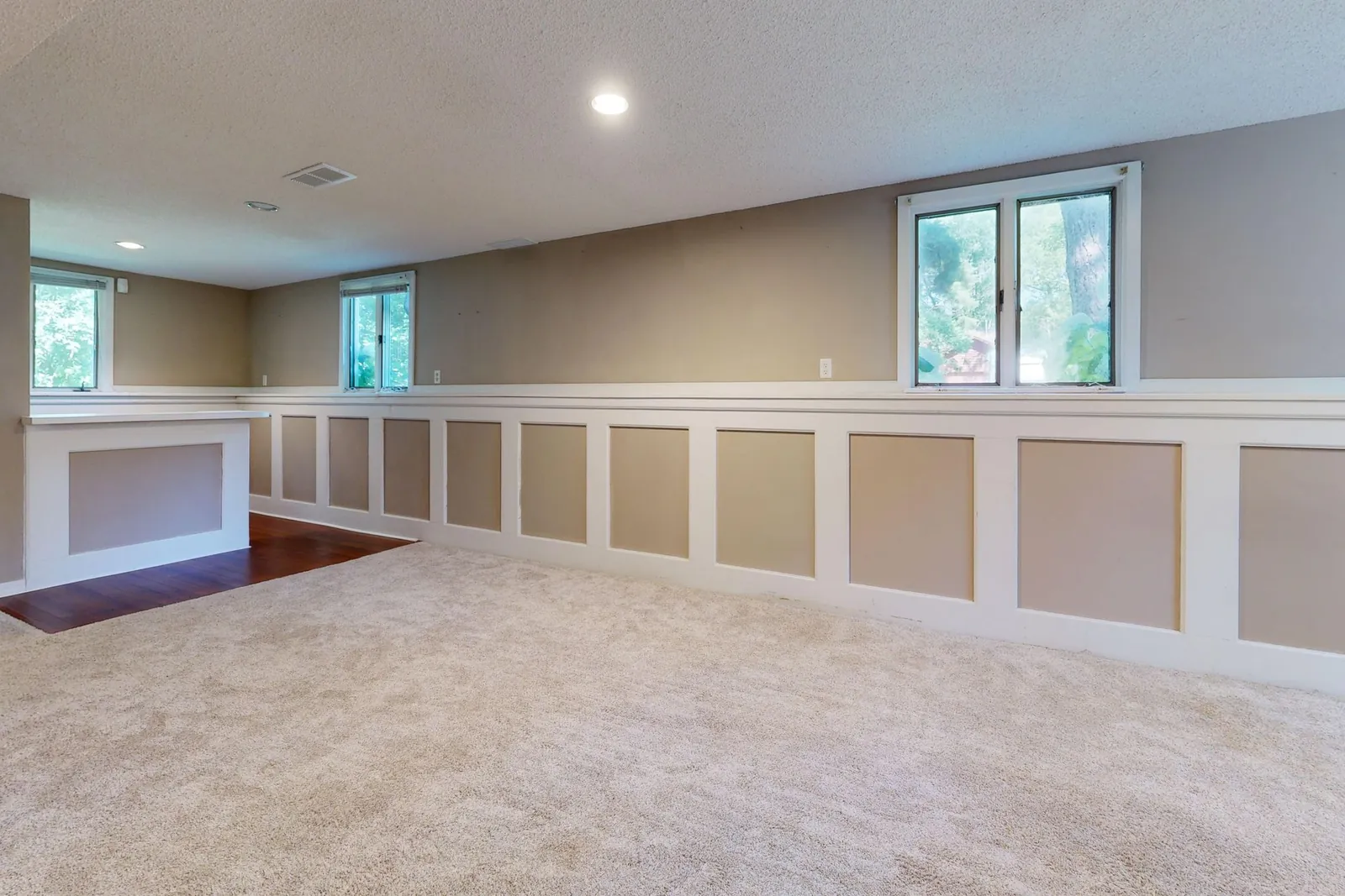 An open finished basement with continuous ceiling and painted wainscoting