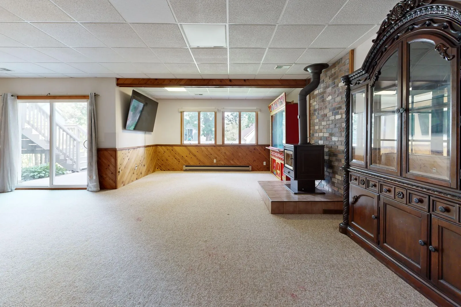 A dated basement divided by a wall and heavy wood trim