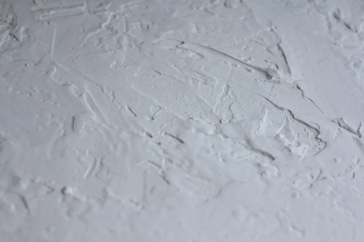 Close-up of a knockdown texture finish on a white wall.