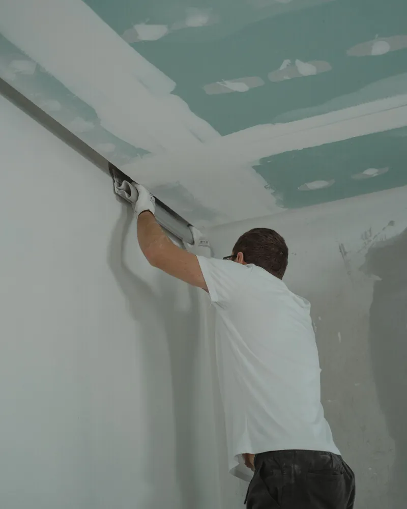A finisher running joint compound along a taped drywall seam.